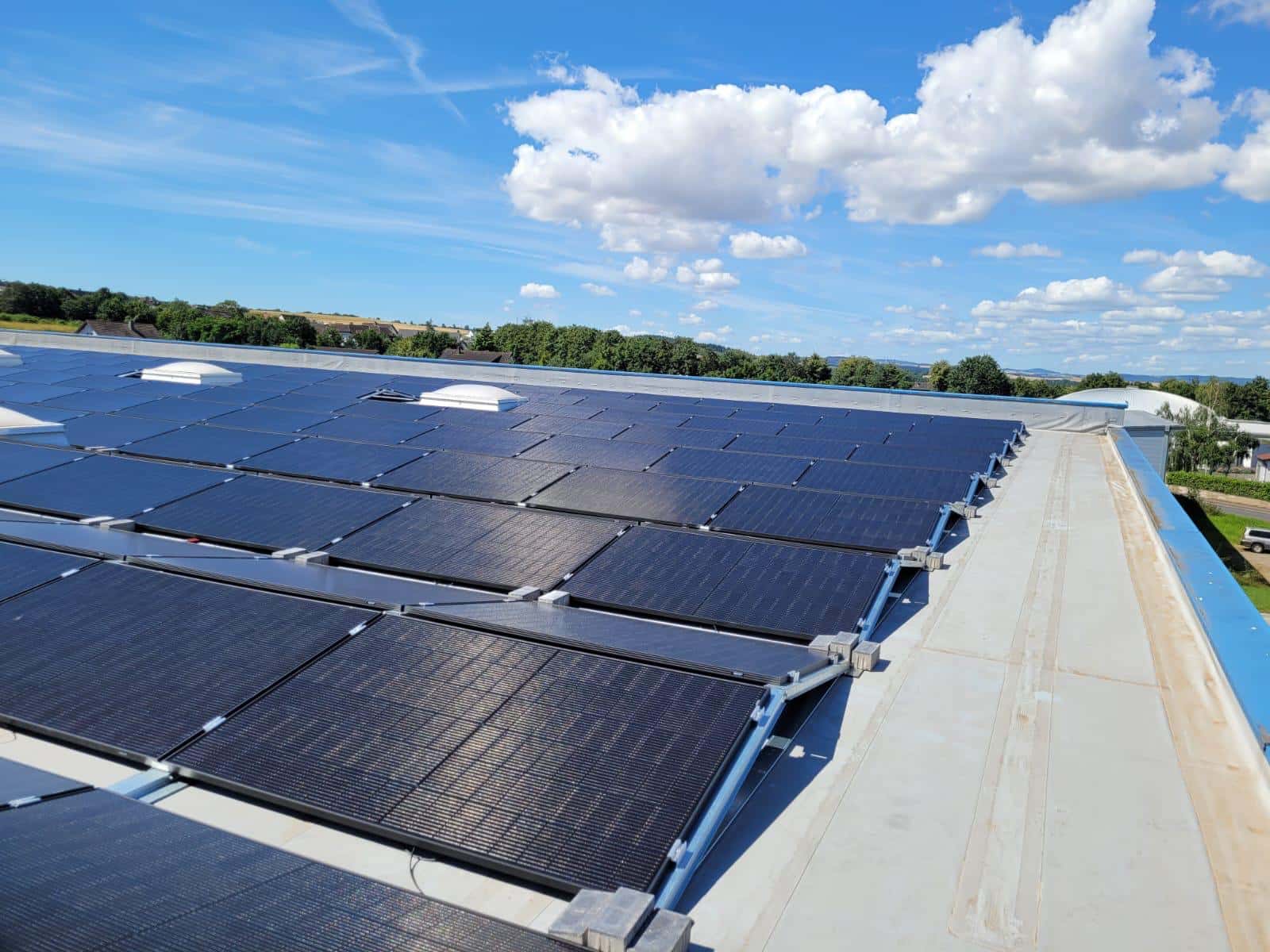 Photovoltaikmodule auf einem großen Hallendach mit Blick über die Landschaft